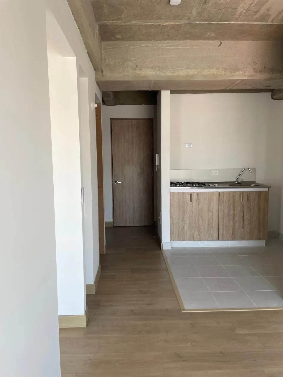Cocina del apartamento vista desde la sala, con el corredor de entrada al costado.