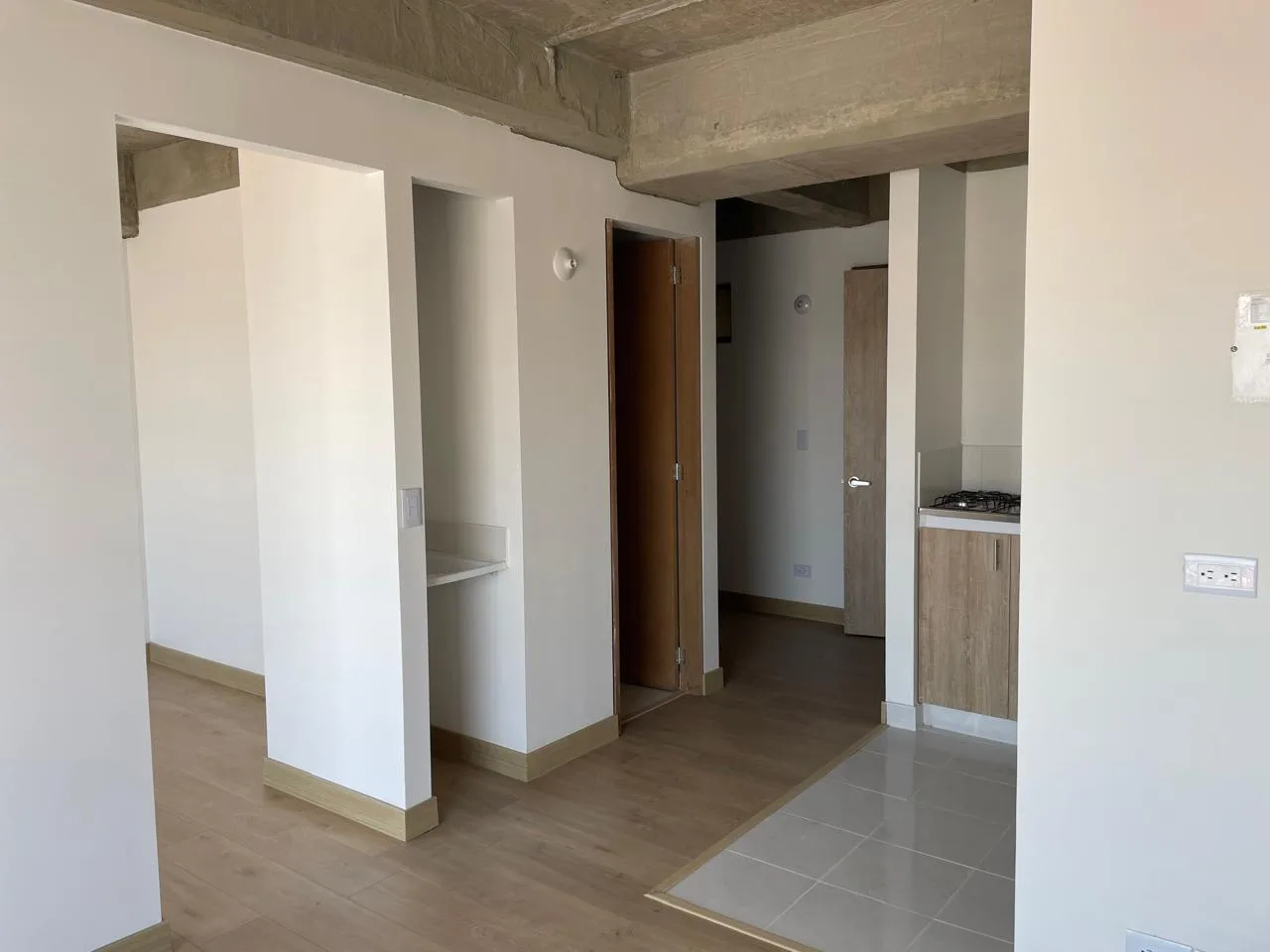 Entrada del apartamento, con el nicho del espacio de estudio a un lado y la cocina al fondo.