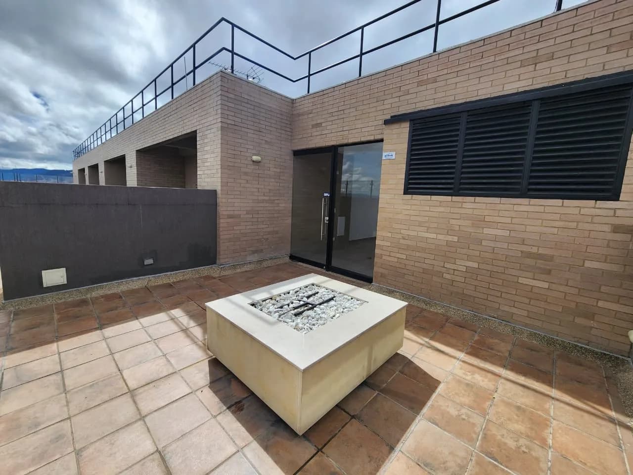 Zona de fogata en la azotea, con un brasero de concreto sobre el piso de terracota.