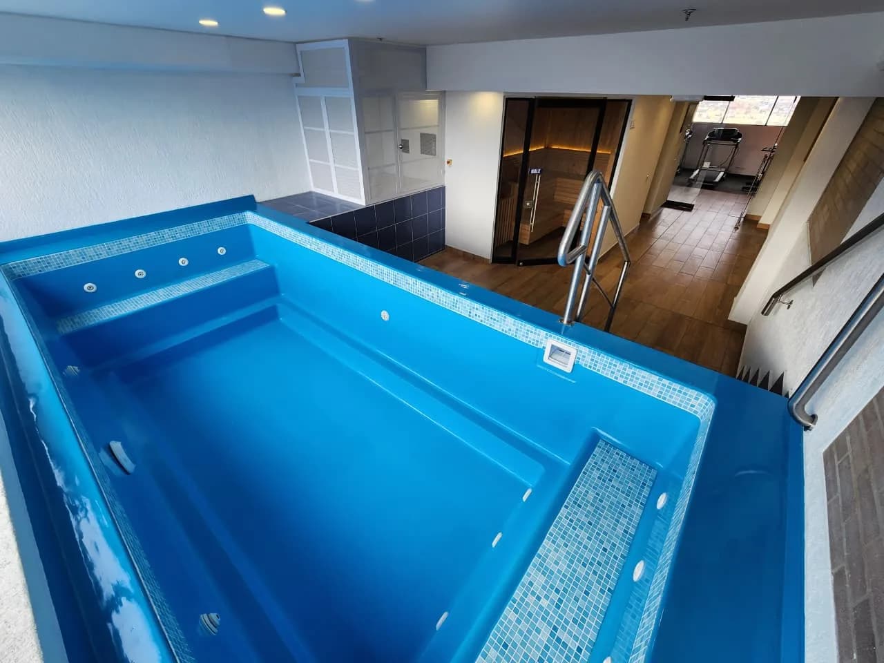 Zona húmeda vista desde arriba: el jacuzzi en primer plano, el sauna y el gimnasio al fondo.